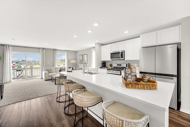 kitchen featuring sink, appliances with stainless steel finishes, white cabinetry, dark hardwood / wood-style floors, and a kitchen bar