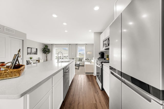 kitchen with sink, white cabinetry, appliances with stainless steel finishes, dark hardwood / wood-style floors, and a large island