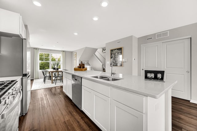 kitchen featuring sink, stainless steel appliances, dark hardwood / wood-style floors, white cabinets, and a center island with sink