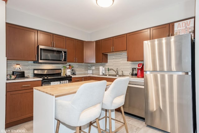 kitchen featuring stainless steel appliances, sink, a breakfast bar area, and decorative backsplash