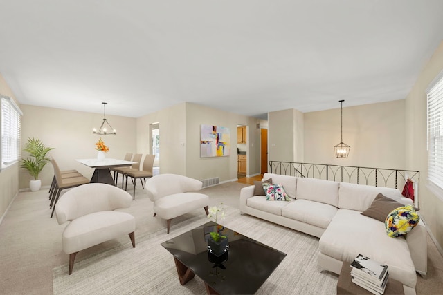 carpeted living room featuring a wealth of natural light and a chandelier