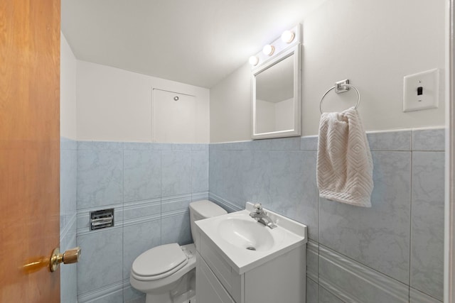 bathroom with vanity, tile walls, and toilet