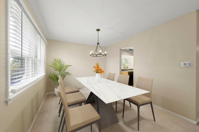 carpeted dining area featuring an inviting chandelier