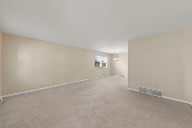 carpeted spare room featuring a chandelier