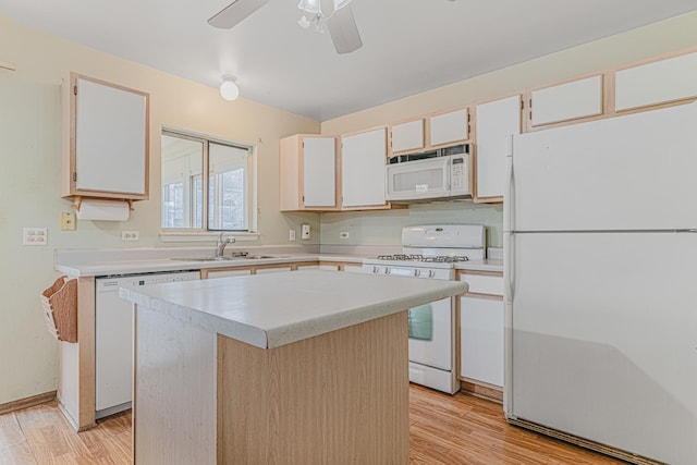 kitchen featuring sink, light wood-type flooring, a kitchen island, white appliances, and white cabinets