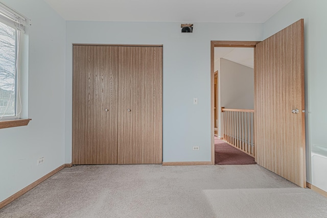 unfurnished bedroom featuring light colored carpet and a closet