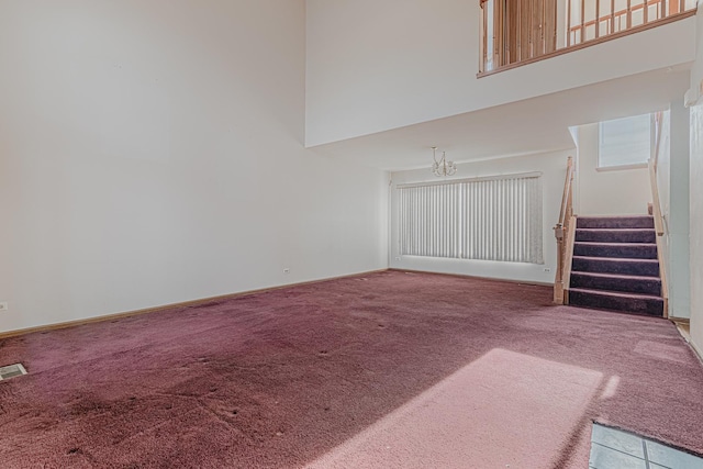 unfurnished living room featuring carpet flooring and a towering ceiling