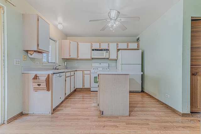 kitchen with white appliances, a center island, sink, and light wood-type flooring