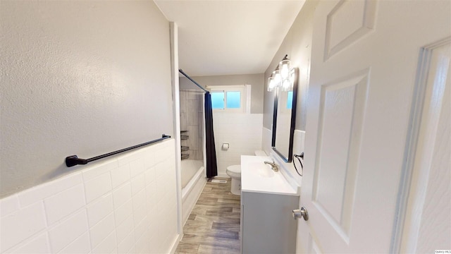 full bathroom with tile walls, vanity, tiled shower / bath combo, and toilet