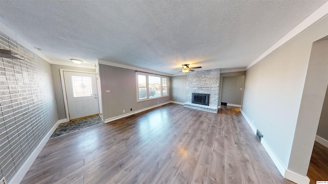 unfurnished living room with hardwood / wood-style flooring, ceiling fan, a textured ceiling, and a fireplace