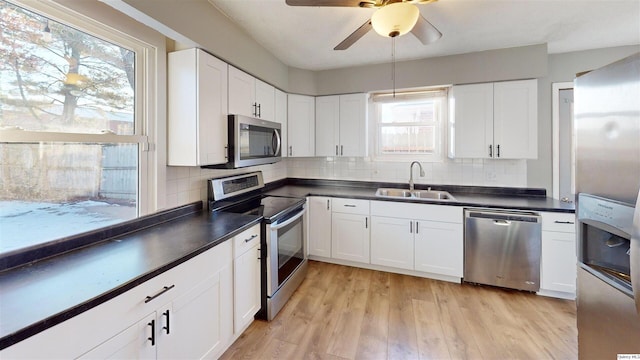 kitchen featuring sink, tasteful backsplash, light wood-type flooring, stainless steel appliances, and white cabinets