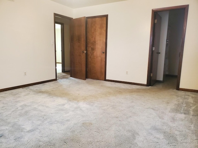 unfurnished bedroom featuring light colored carpet and a closet