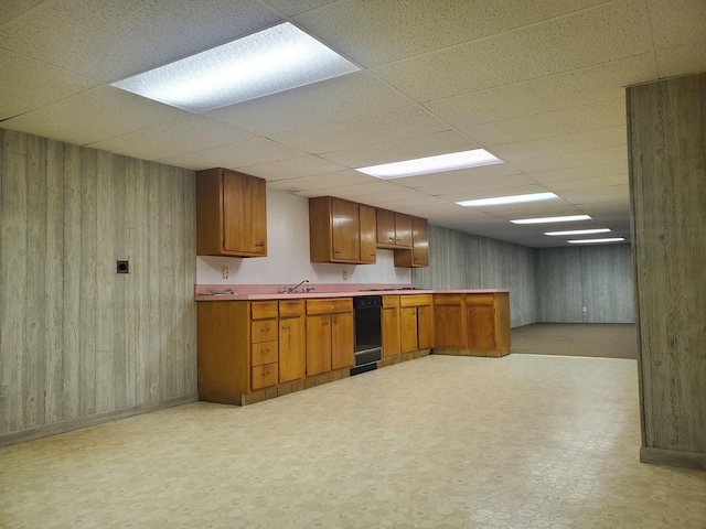 kitchen featuring a drop ceiling, sink, and wood walls