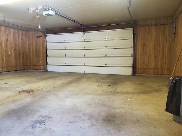 garage with a garage door opener and wood walls