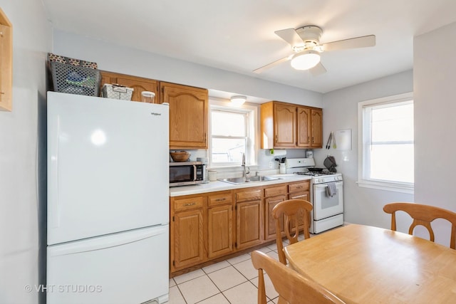 kitchen with sink, white appliances, light tile patterned floors, and ceiling fan