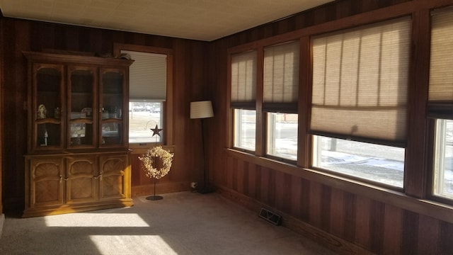 unfurnished dining area with wood walls, carpet, and visible vents