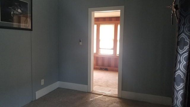 empty room featuring carpet, visible vents, and baseboards