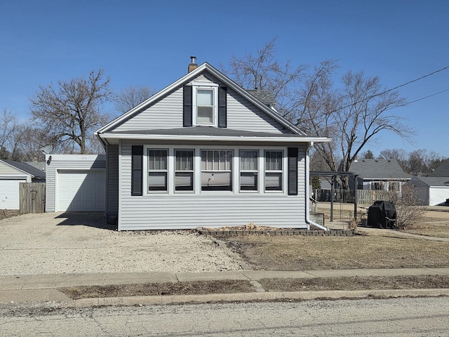 bungalow with an outbuilding, driveway, fence, an attached garage, and a chimney