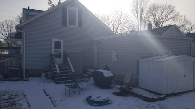 snow covered property with a shed and an outbuilding