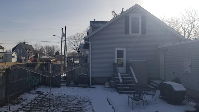 snow covered rear of property with fence