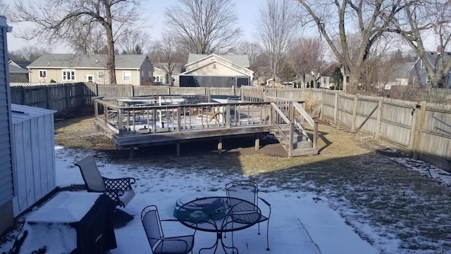 yard layered in snow featuring a fenced backyard, a wooden deck, and a residential view