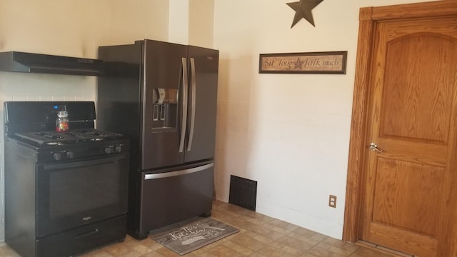 kitchen with black range with gas cooktop, stainless steel fridge, visible vents, light floors, and under cabinet range hood