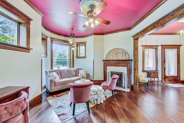 living area featuring a fireplace with flush hearth, crown molding, baseboards, and dark wood-style flooring