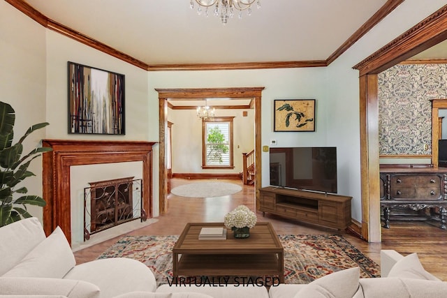 living area with a chandelier, a fireplace with flush hearth, light wood-style flooring, and crown molding