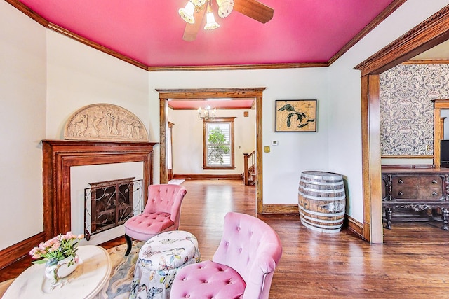 living area with baseboards, a fireplace with flush hearth, ornamental molding, and wood finished floors