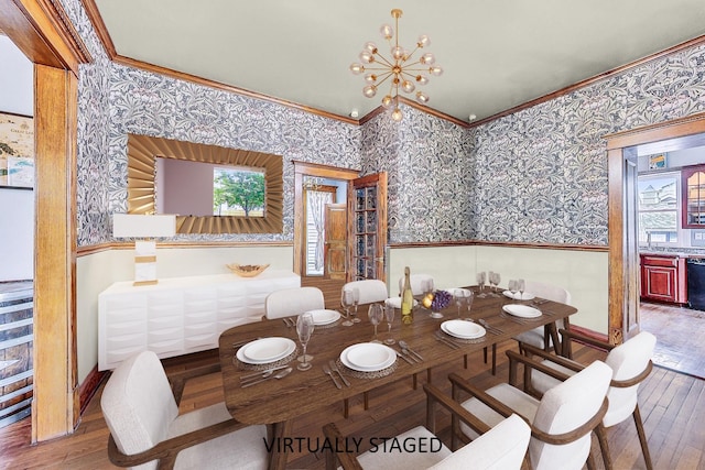 dining room with wallpapered walls, ornamental molding, and wood finished floors