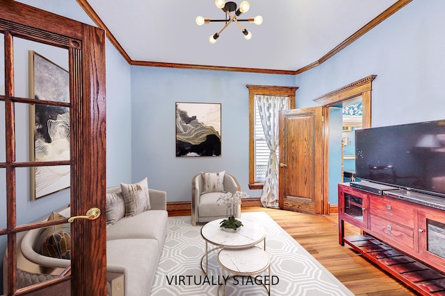 living area with a chandelier, ornamental molding, light wood-style flooring, and baseboards