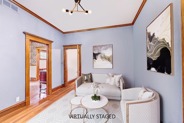 living room featuring a chandelier, visible vents, baseboards, light wood finished floors, and crown molding