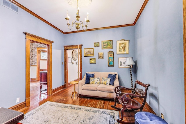 living room featuring crown molding, wood finished floors, visible vents, baseboards, and an inviting chandelier