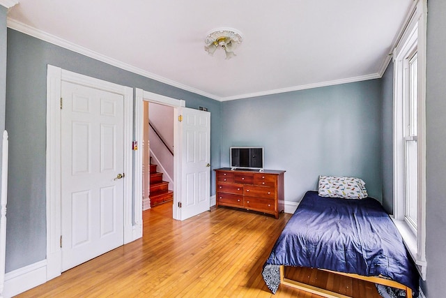 bedroom with light wood-type flooring, baseboards, and ornamental molding