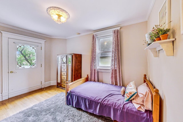 bedroom featuring ornamental molding, multiple windows, and light wood-type flooring