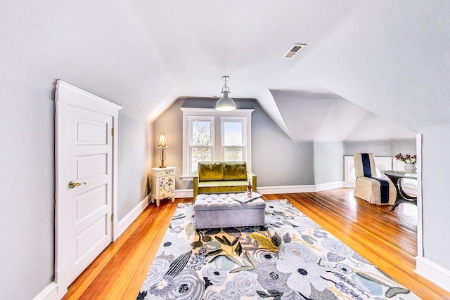 sitting room featuring vaulted ceiling, wood finished floors, visible vents, and baseboards