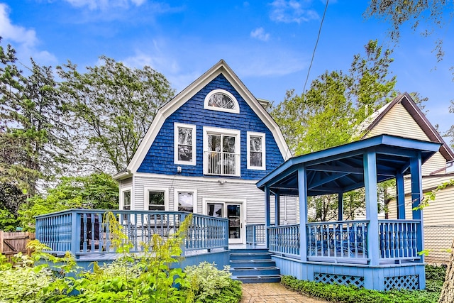 rear view of property with a wooden deck, a gambrel roof, and a gazebo