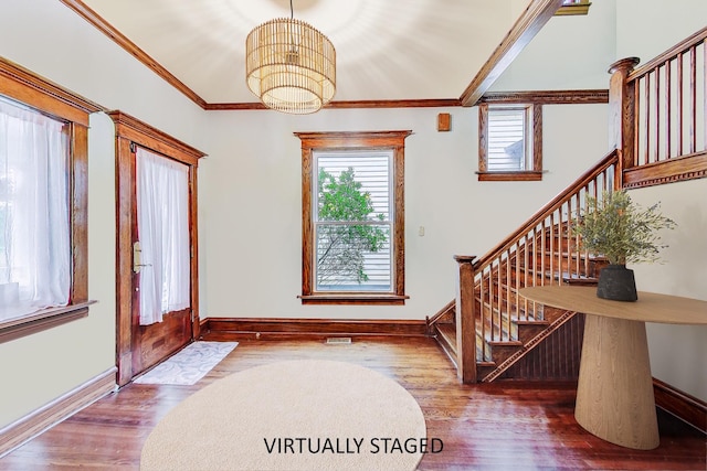 entryway with a healthy amount of sunlight, wood finished floors, and crown molding