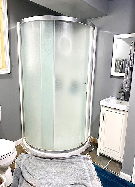 bathroom featuring vanity, an enclosed shower, tile patterned floors, and toilet