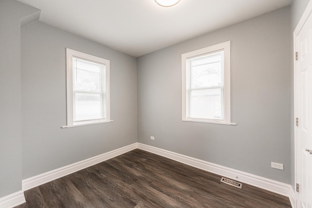 spare room featuring a healthy amount of sunlight and dark hardwood / wood-style floors