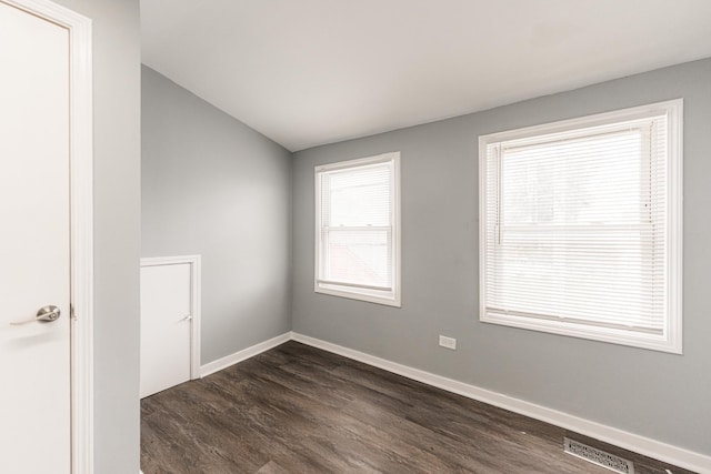 spare room featuring vaulted ceiling and dark hardwood / wood-style flooring