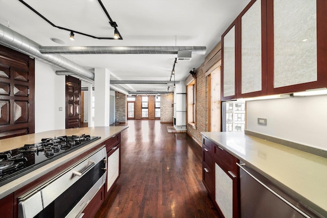 kitchen featuring gas stovetop, brick wall, dark hardwood / wood-style floors, and track lighting