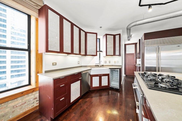 kitchen with wine cooler, appliances with stainless steel finishes, light countertops, glass insert cabinets, and dark wood-style flooring