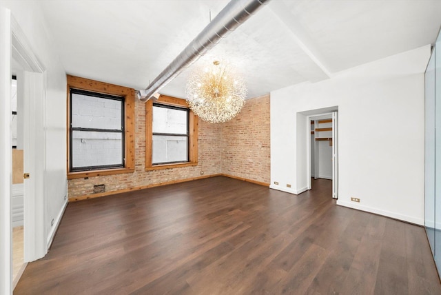 interior space featuring brick wall, dark hardwood / wood-style floors, and a notable chandelier