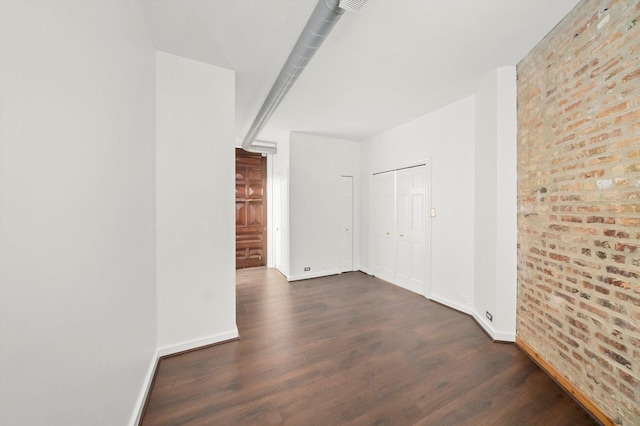 spare room with brick wall and dark hardwood / wood-style flooring