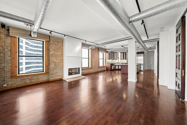 unfurnished living room featuring a fireplace, dark hardwood / wood-style floors, and brick wall