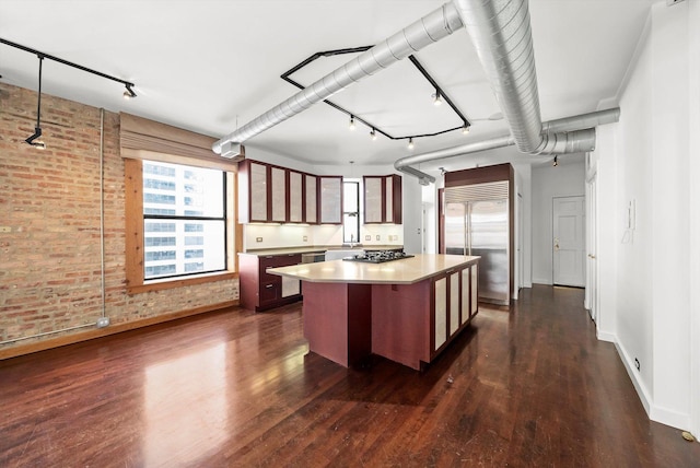 kitchen featuring brick wall, dark hardwood / wood-style floors, pendant lighting, a center island, and stainless steel appliances