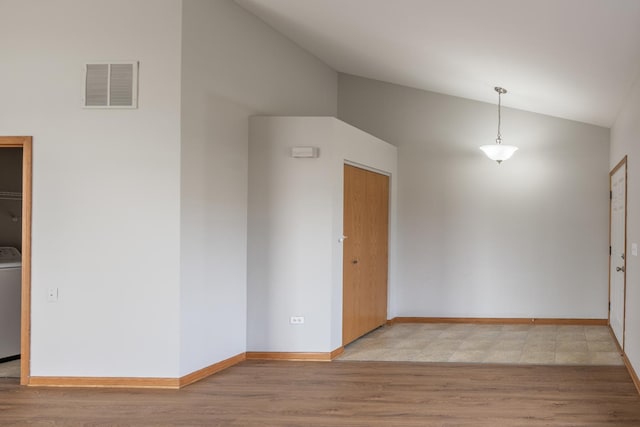 unfurnished room featuring washer / clothes dryer, lofted ceiling, and light hardwood / wood-style floors