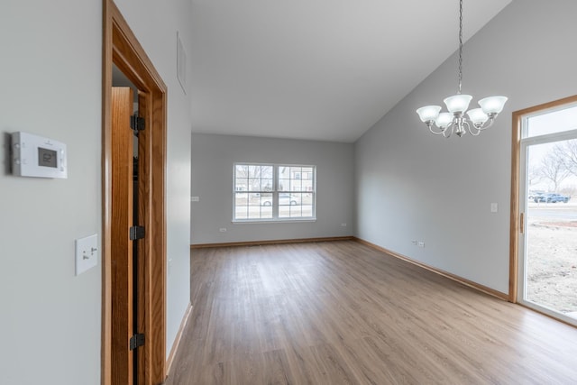 unfurnished room featuring an inviting chandelier, light hardwood / wood-style floors, and lofted ceiling