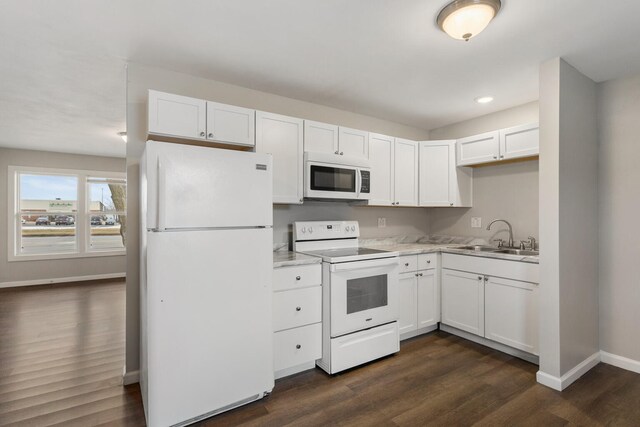 kitchen with sink, white appliances, dark wood-type flooring, and white cabinets